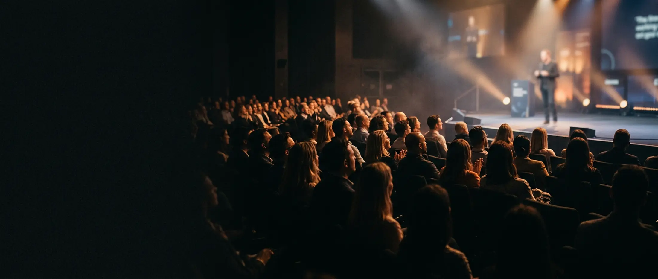 Conference audience watching speaker on stage with dramatic lighting